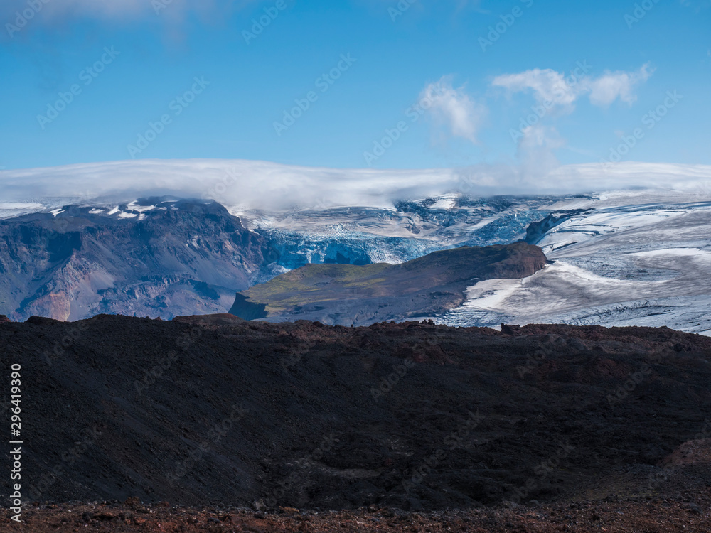 View over a landscape of Godland and thorsmork with the Eyjafjallajokull glacier and volcano, lava formations, snow, ice and green moss. Iceland, Fimmvorduhals hiking trail. Summer cloudy day.