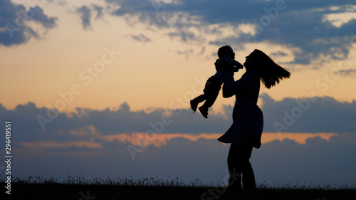 Baby walks first steps to mother raise up and spin at sunset outdoor