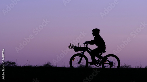 Fototapeta Naklejka Na Ścianę i Meble -  Child silhouette riding bike on hill close sunset sky, isolated kid in nature