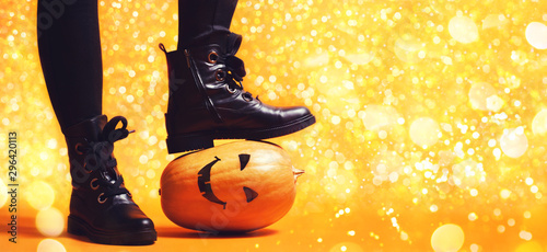 Legs of witch standing on scary pumpkin.