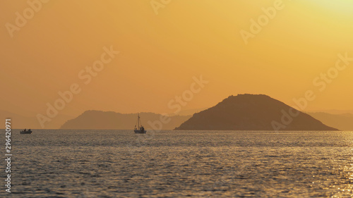 Evening landscape,far away boats sail on island sea water, colorful sky, magical