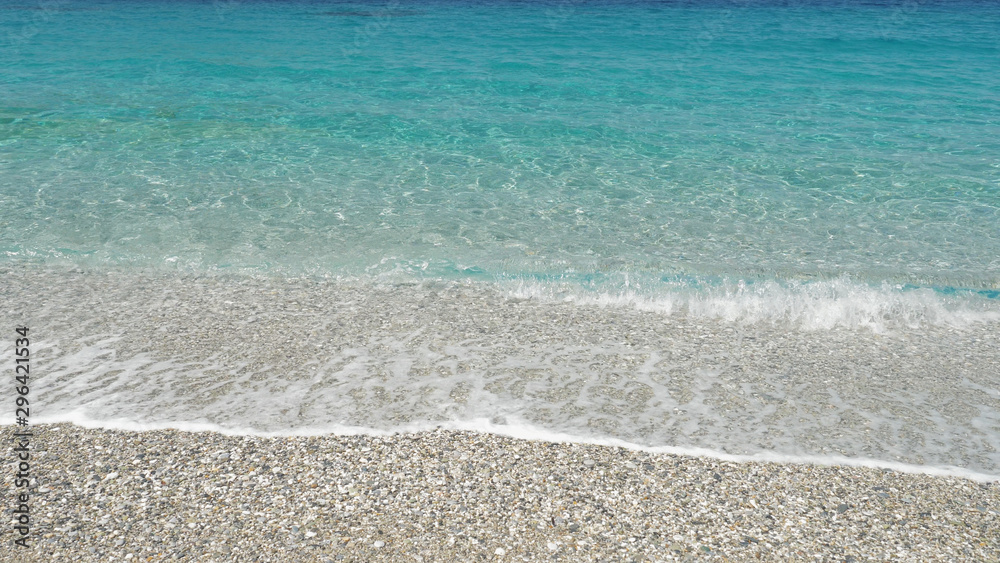 Crystal clear turquoise shallow sea water waves washing the beach