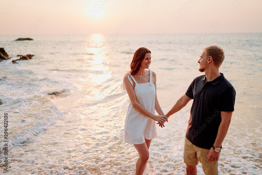 Romantic dating. Young loving couple walking together by the sand beach enjoying the sea view.