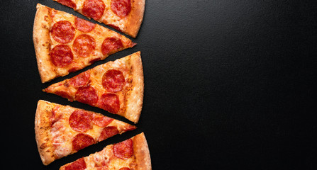 Pepperoni pizza slice on black slate background. Banner. Copy space. Pizza restaurant menu