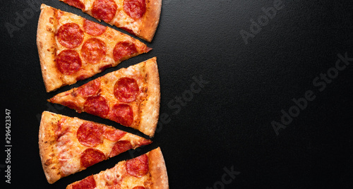 Pepperoni pizza slice on black slate background. Banner. Copy space. Pizza restaurant menu