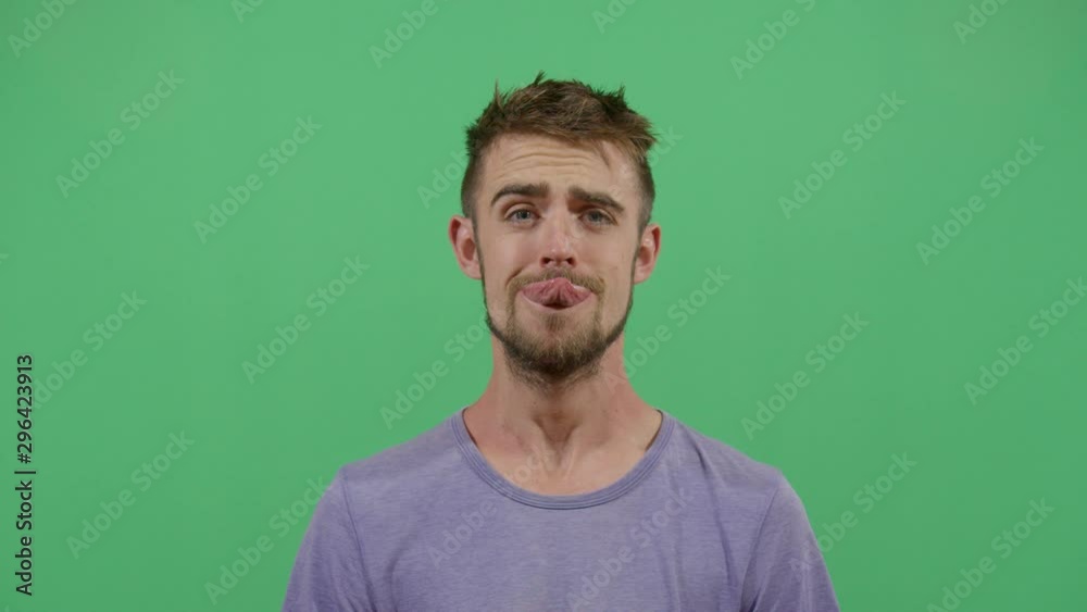 Adult Man Trying To Reach The Nose With The Tongue Starting From A Relaxed State And Going Into An Unpredictable Funny Face. Studio Isolated Shot Against Green Screen Background Adult Man Trying To Reach The Nose With The Tongue Starting From A Relaxed State And Going Into An Unpredictable Funny Face. Studio Isolated Shot Against Green Screen Background