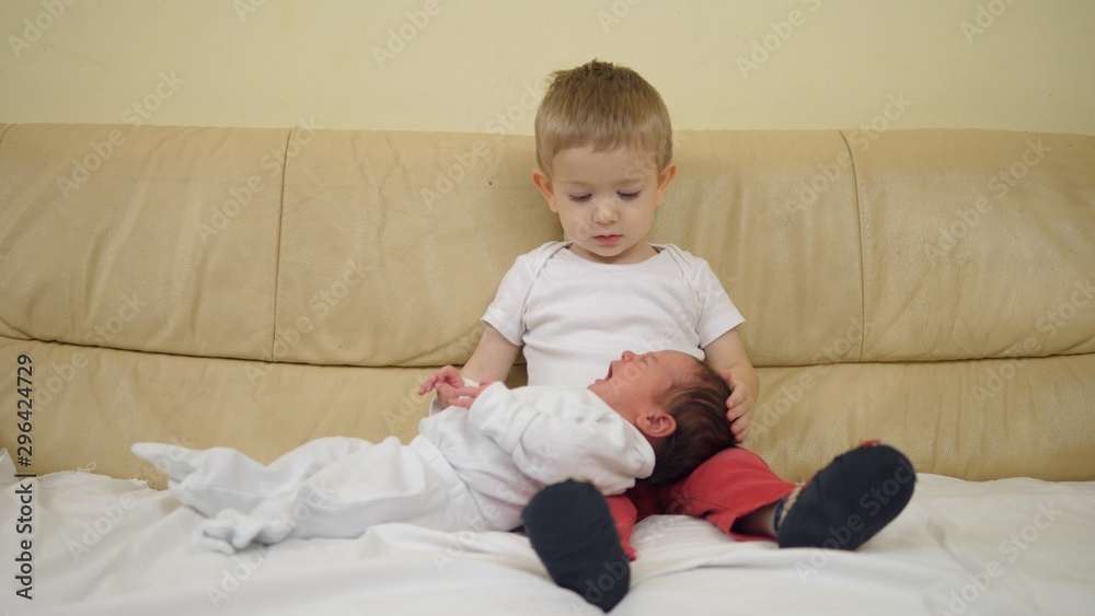 Funny little brother with crying newborn baby child in his lap Funny little brother with crying newborn baby child in his lap