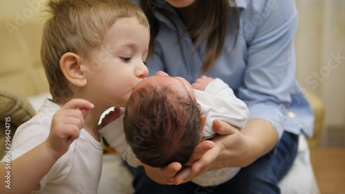 Focus on newborn in mother arms  brother give a kiss to baby