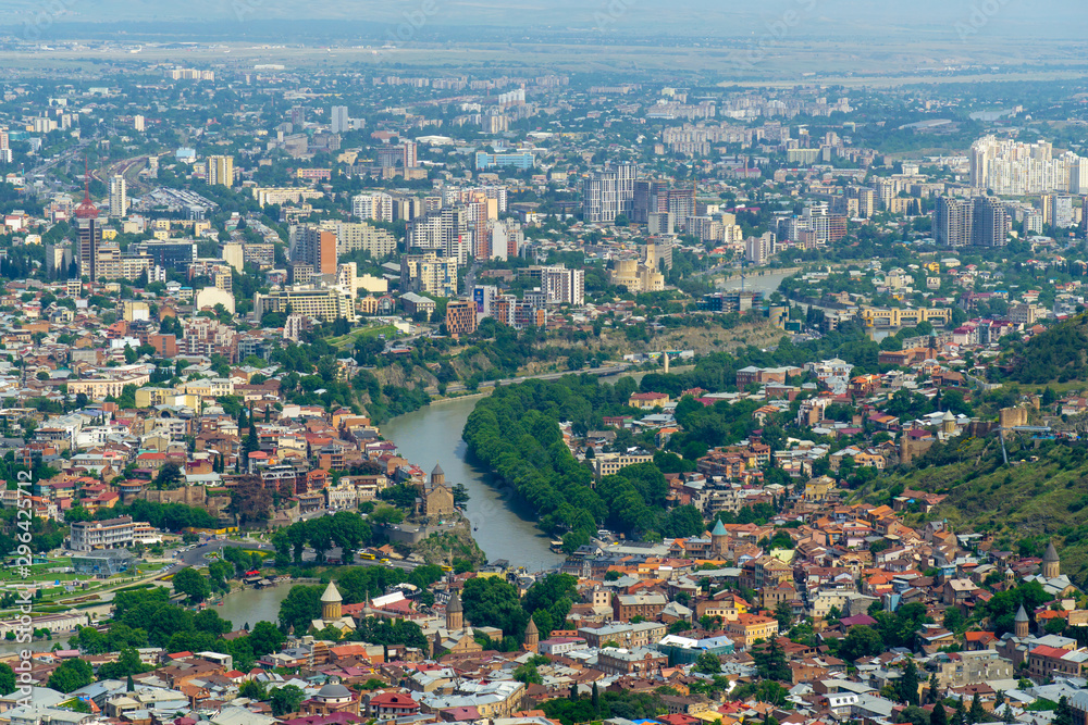 TBILISI, GEORGIA, JUNE 3, 2019: Aerial view from the Narikala fortress on the Tbilisi city, the capital of Georgia, full of small tiled roof houses, green trees, bridges over the Kura river TBILISI, GEORGIA, JUNE 3, 2019: Aerial view from the Narikala fortress on the Tbilisi city, the capital of Georgia, full of small tiled roof houses, green trees, bridges over the Kura river
