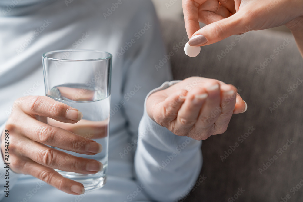 Caring nurse giving pills to senior woman with glass of water in hand Caring nurse giving pills to senior woman with glass of water in hand