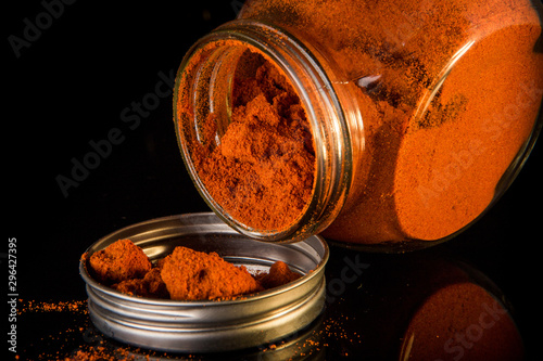 milled red paprika poured from glass jar on metal cover