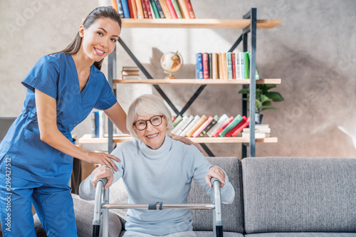 Female asian nurse helping senior woman to get up with walker at home