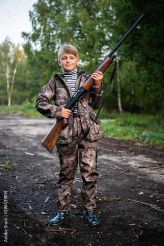 Father gave a son a shotgun rifle to carry. Happy boy prepared for hunding with his father together.