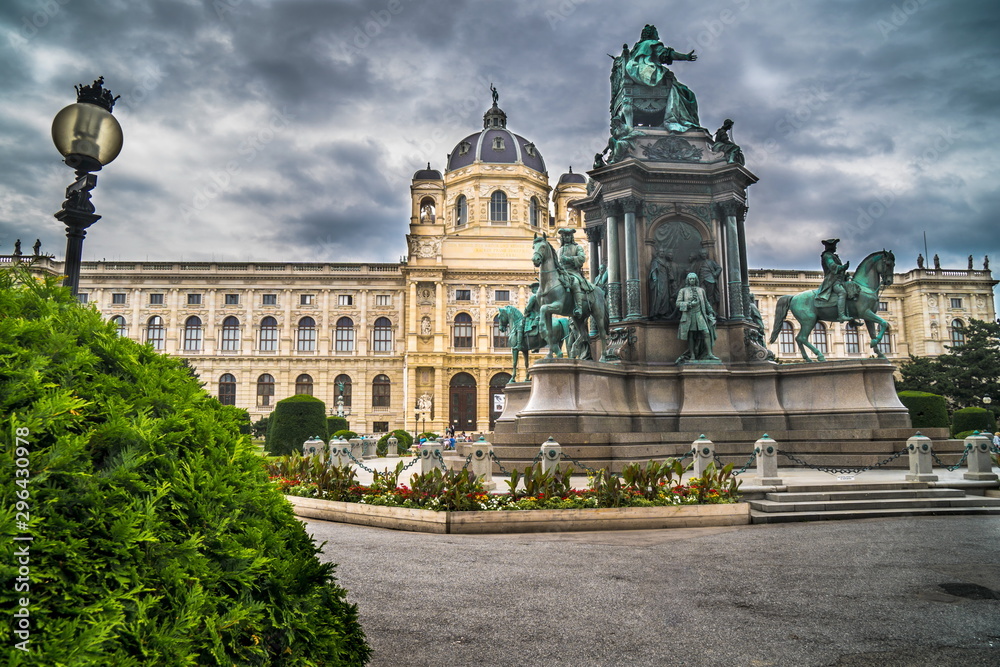 Natural History Museum in Vienna with green hedge and monument in cloudy background and street lamp