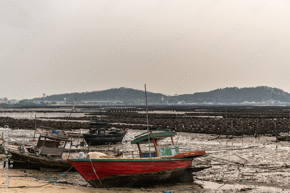 Ban Bai Bua, Thailand - March 16, 2019: Large Oyster beds and banks in the Gulf of Thailand just off shore with forested hills in back. Three stranded sloops during low tide under cloudy sky. Ban Bai Bua, Thailand - March 16, 2019: Large Oyster beds and banks in the Gulf of Thailand just off shore with forested hills in back. Three stranded sloops during low tide under cloudy sky.