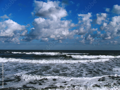 Stormy day on sea coast with beautiful blue sky with clouds and white waves nature background