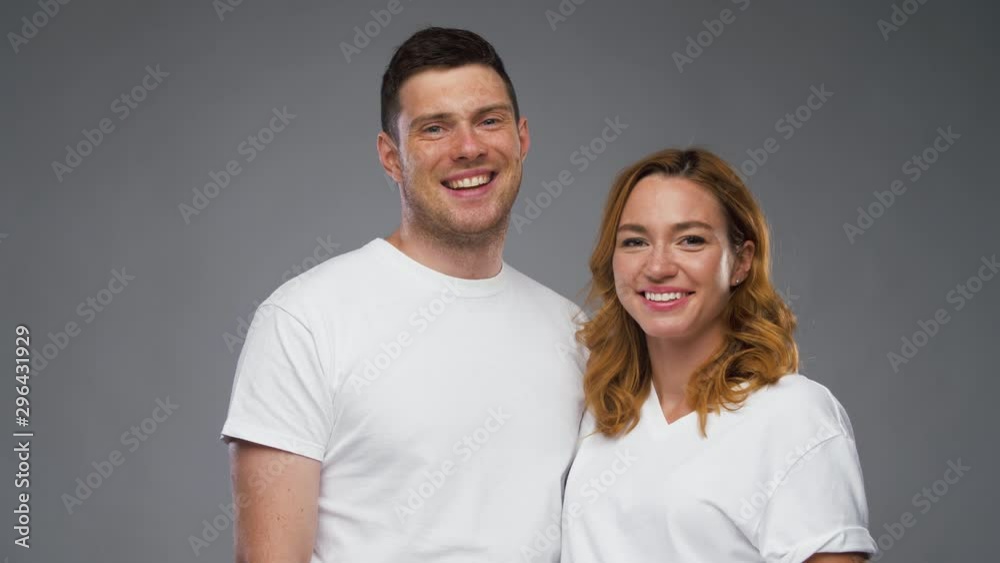 fashion, style and people concept - happy smiling couple in white t-shirts over grey background fashion, style and people concept - happy smiling couple in white t-shirts over grey background