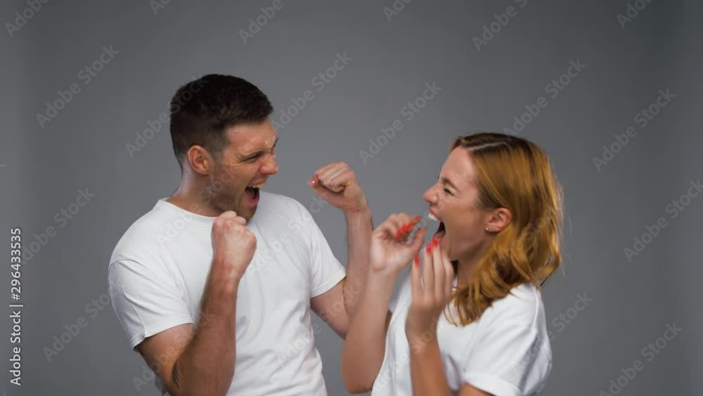 success, winning and happiness concept - happy couple in white t-shirts celebrating triumph over grey background success, winning and happiness concept - happy couple in white t-shirts celebrating triumph over grey background