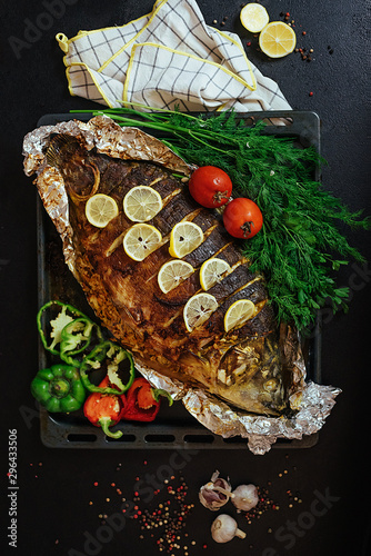 Baked fish river carp with aromatic herbs, spices, salt, vegetables, lemon, garlic, top view, healthy food, diet or cooking concept.