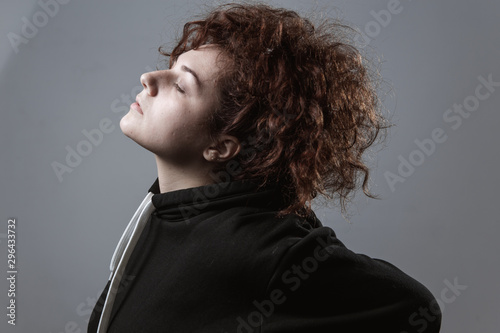 Portrait of a beautiful curly-haired girl with redheads on a gray background