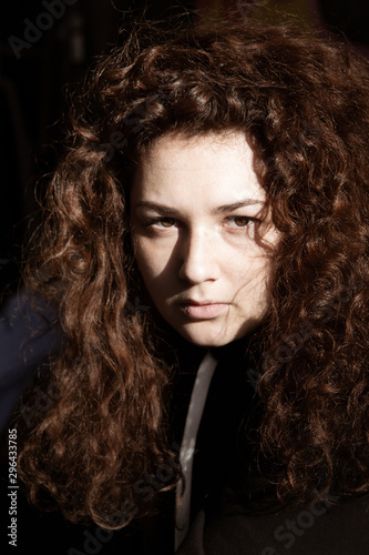 Portrait of a beautiful curly-haired girl with redheads on a gray background