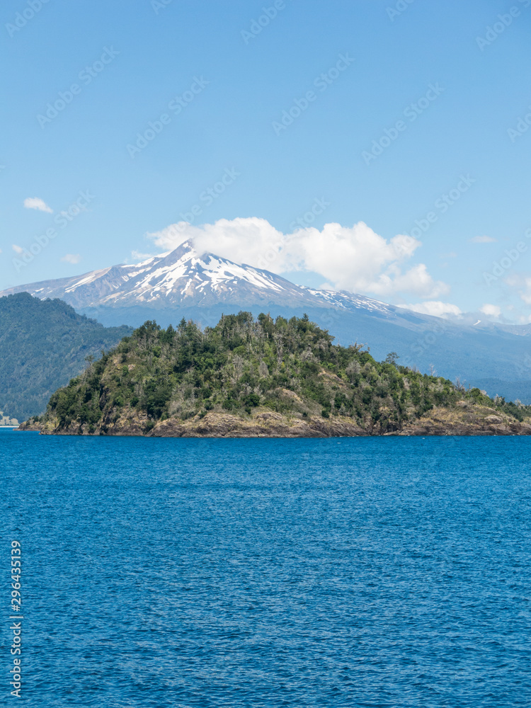 The amazing Choshuenco Volcano surrounded by clouds, over the waters of Lake Panguipulli, in southern Chile.