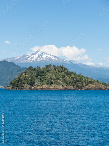The amazing Choshuenco Volcano surrounded by clouds, over the waters of Lake Panguipulli, in southern Chile.