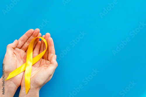 Disease control concept. Orange ribbon in hands on blue background top view space for text