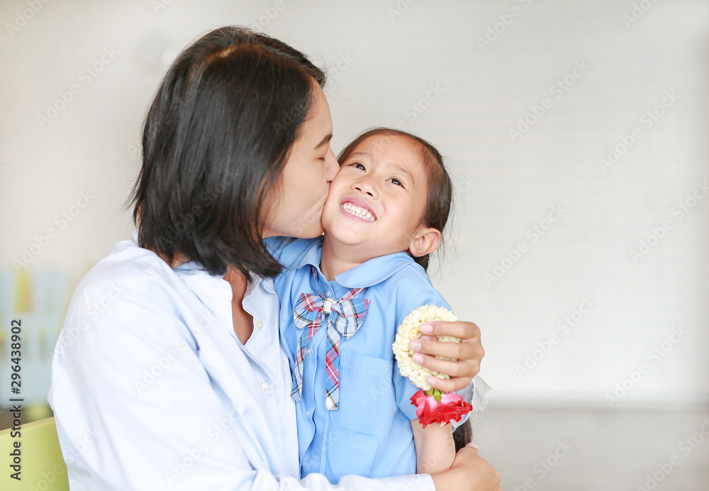 Portrait of Asian mom kissing and hugging her daughter on Mother's day