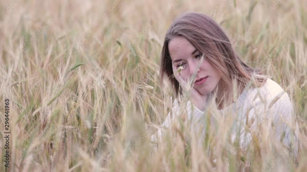 Beautiful young girl in a white sweater sits in a wheat field. Beautiful young girl in a white sweater sits in a wheat field.