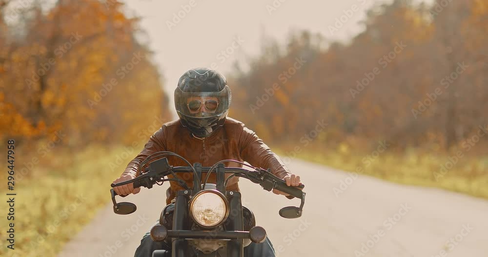 Brutal man in glasses and a helmet rides on the highway on a motorcycle. Golden autumn. Brutal man in glasses and a helmet rides on the highway on a motorcycle. Golden autumn.