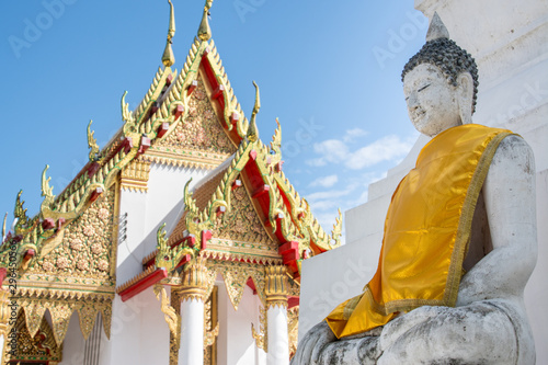 White buddha with yellow clothes near temple