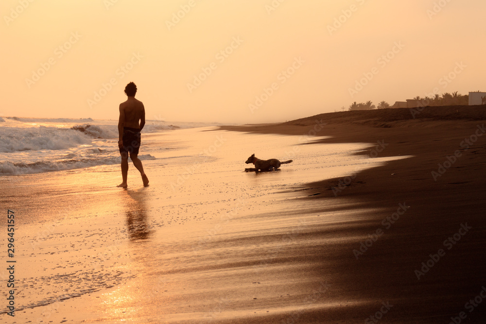 silhouette of man and his dog walking on beach at sunset in guatemala