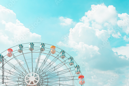 Retro pastel colorful ferris wheel of the amusement park in the blue sky  and cloud background. photo