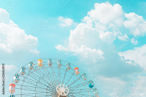 Retro pastel colorful ferris wheel of the amusement park in the blue sky and cloud background.