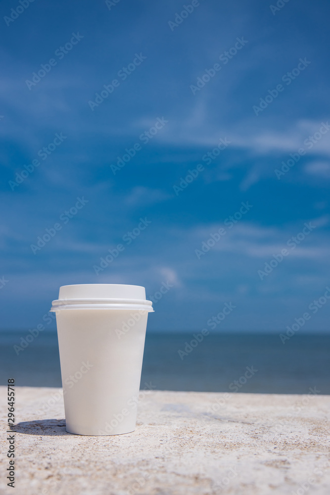 takeaway cup of coffee on the beach and blue sky background takeaway cup of coffee on the beach and blue sky background