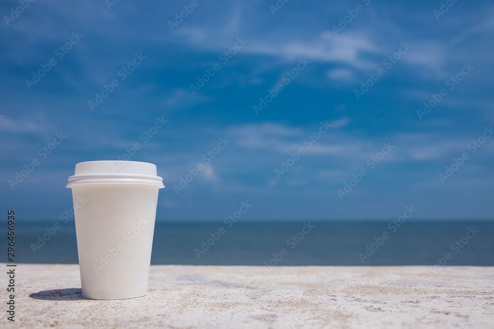 takeaway cup of coffee on the beach and blue sky background takeaway cup of coffee on the beach and blue sky background