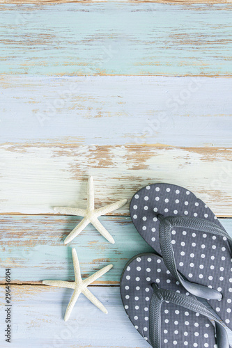 Cute grey polkadot slippers with star fish grunge wooden background feel like summer season and traveling to the beach.