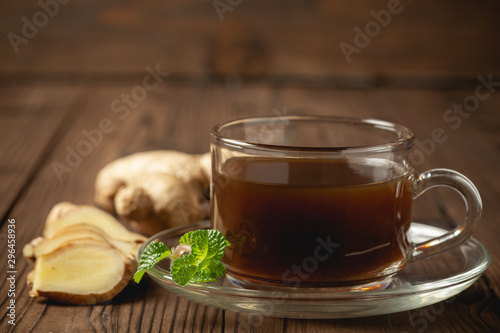 Hot ginger juice and ginger sliced on wooden table.