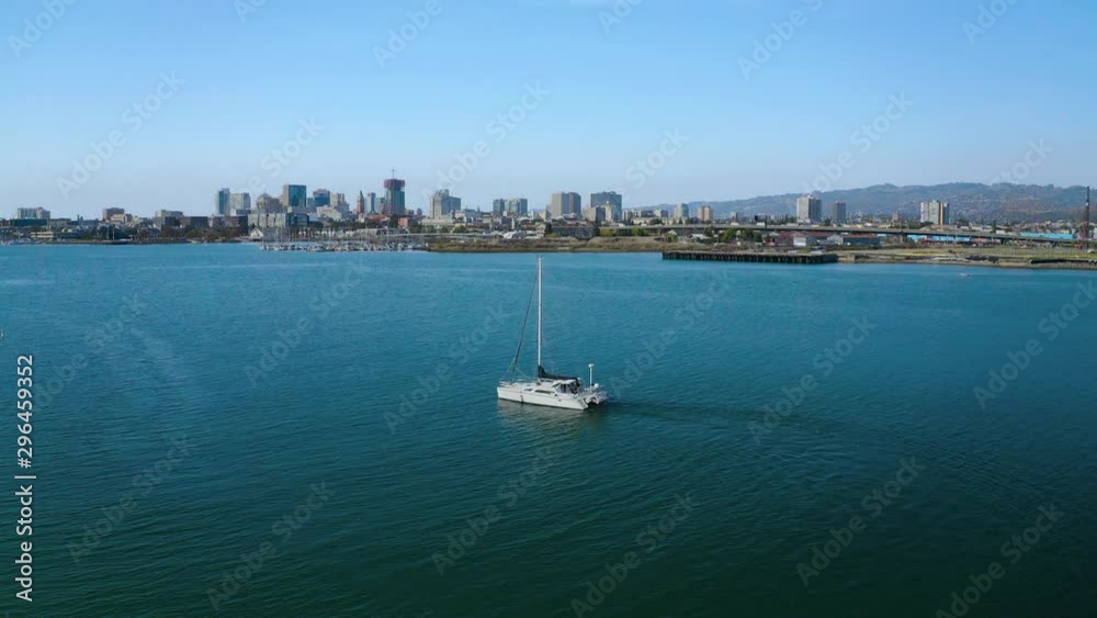 A lone sailboat is drifting with the wind in a beautiful bay on the sunny day.