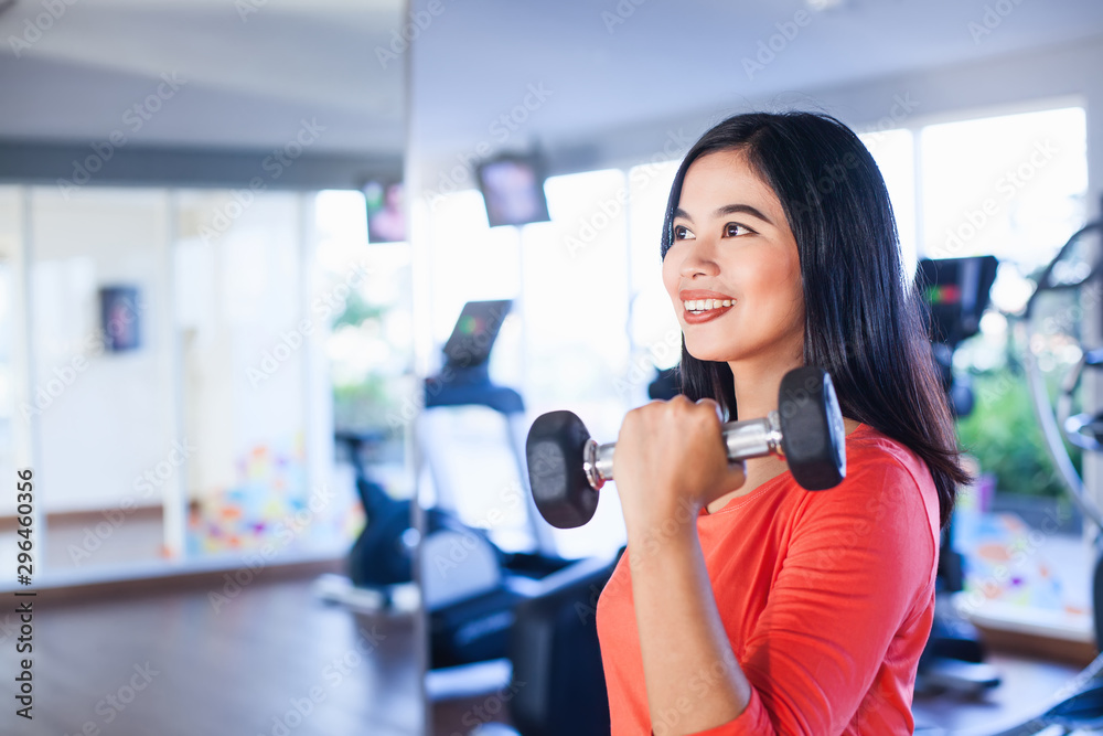 Pretty indonesian woman lifting weights in gym Pretty indonesian woman lifting weights in gym