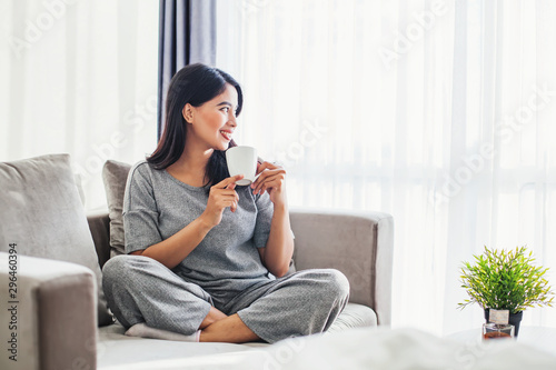 Young asian woman drinking coffee on a sofa bed at home