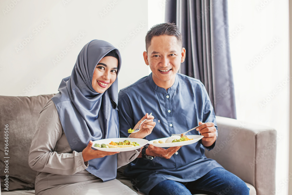 Beautiful muslim southeast asian couple eating together, looking at camera Beautiful muslim southeast asian couple eating together, looking at camera