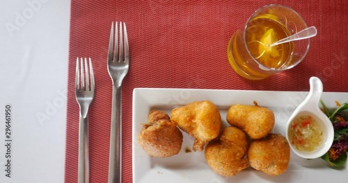 traveling shot of cod fritters, accras de morue, french Caribbean style holiday food on white rectangle plate with rum and white and red table photo