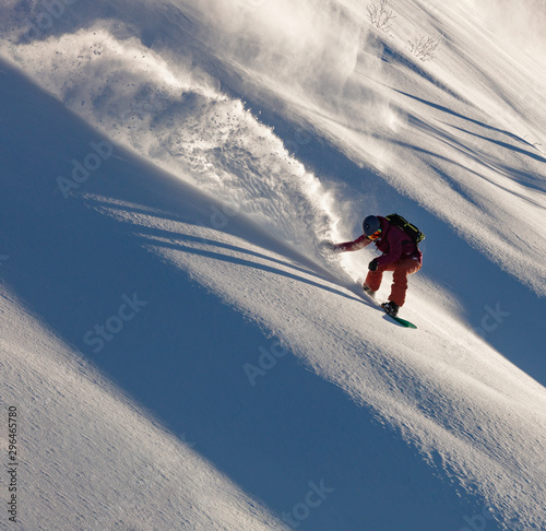 Extreme snowboarder has fun riding fresh powder snow off piste in white mountains. Pro rider snowboarding and carving freshly fallen snow in mountain wilderness. winter extreme sports background