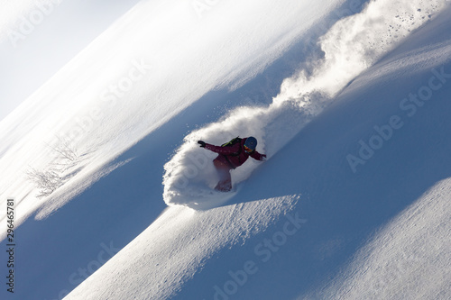 Extreme snowboarder has fun riding fresh powder snow off piste in white mountains. Pro rider snowboarding and carving freshly fallen snow in mountain wilderness. winter extreme sports background