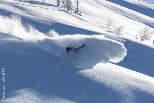 Extreme snowboarder has fun riding fresh powder snow off piste in white mountains. Pro rider snowboarding and carving freshly fallen snow in mountain wilderness. winter extreme sports background