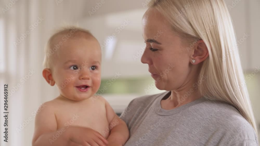 Sophisticated mother holding her son smiling to him and making funny grimace. Nursery concept. isolated, on blurred background Sophisticated mother holding her son smiling to him and making funny grimace. Nursery concept. isolated, on blurred background