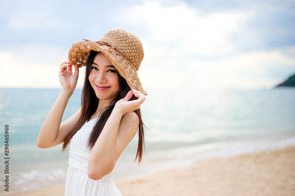 Beautiful girl young woman asia in a  hat smiling on the beach at sunset,enjoy summer vacation on the beach.