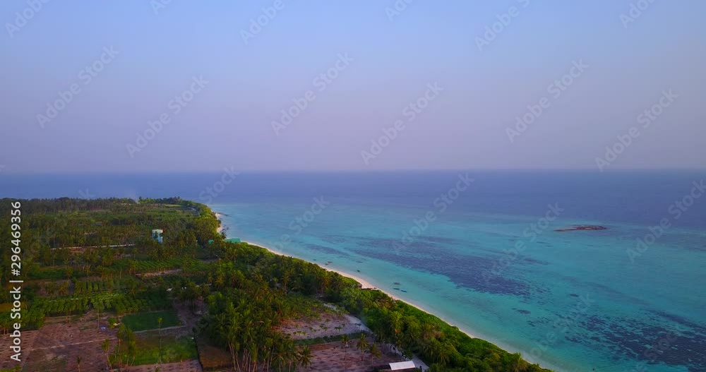 Thailand aerial shot over vegetated, calm, peaceful island. Blue water on horizon. 